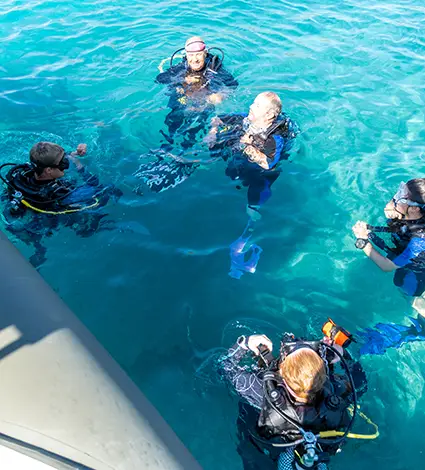 People in a circle with scuba diving equipment in Tolo