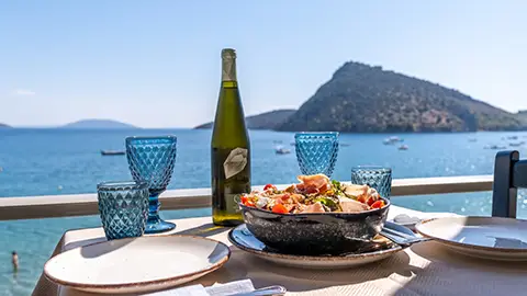 Table in Tolo taverna on the beach with salad and wine served