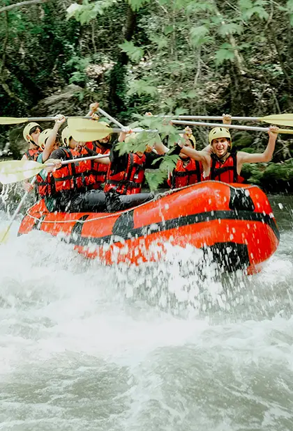 Group of people in a red blowup boat going down a river 