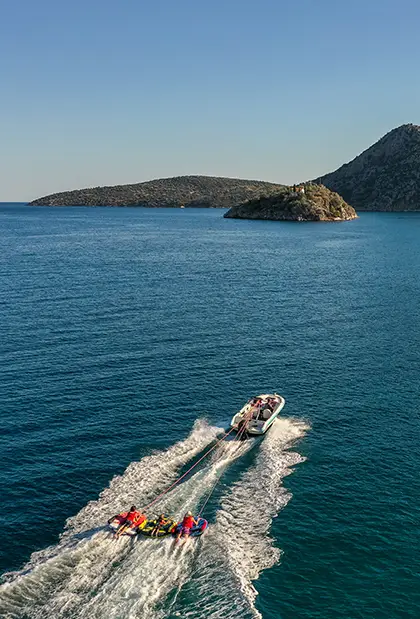 Boat pulling three ringo rides in Tolo with islet in the background