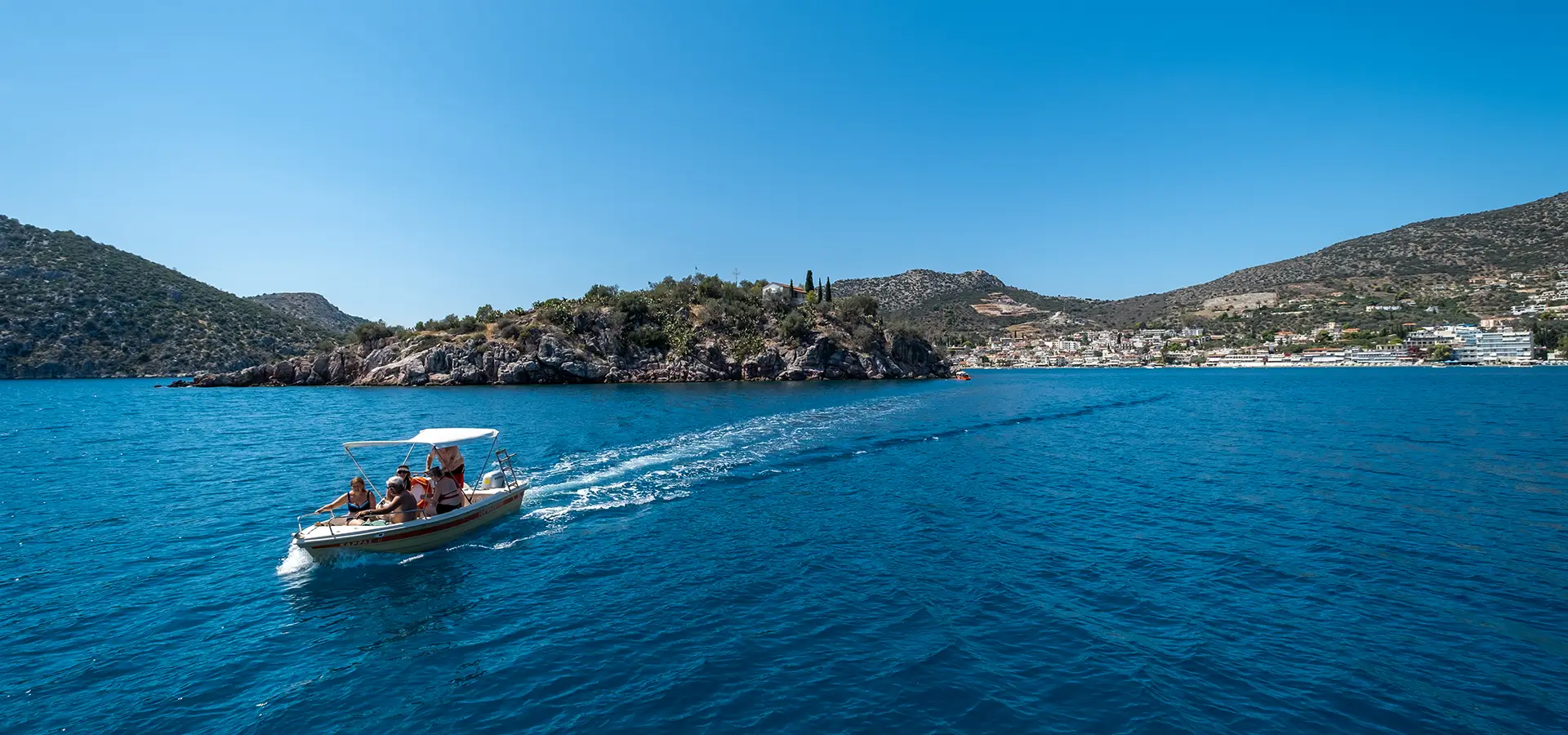 Rental boat in the sea in front of small island called Koronisi